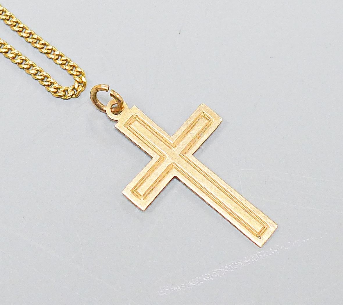 An 18ct yellow gold fine curb-link necklet, 51cm, 5 grams and a 9ct crucifix, 0.8 grams.